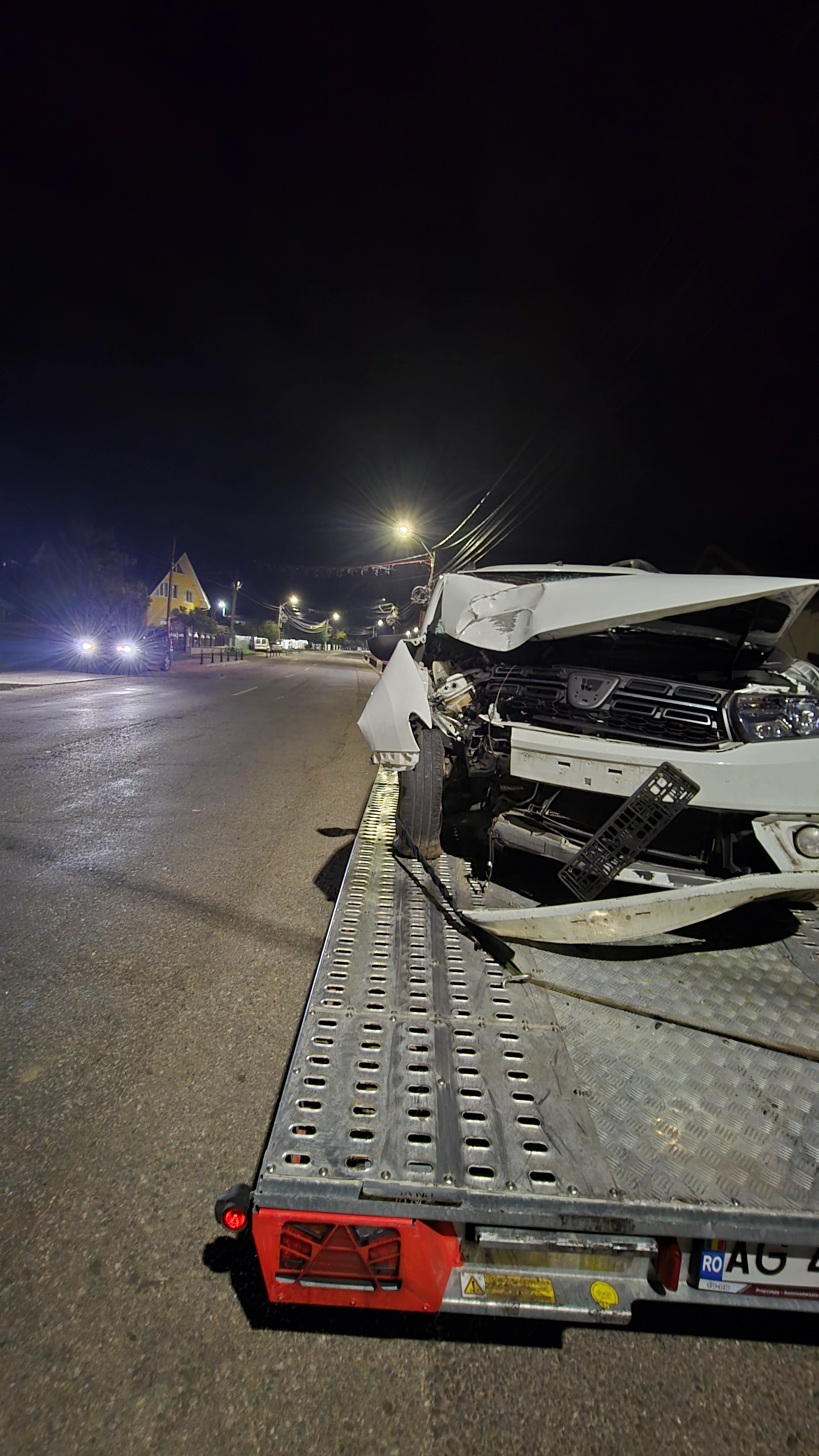 Dacia Logan avariată transportată pe platformă noaptea
